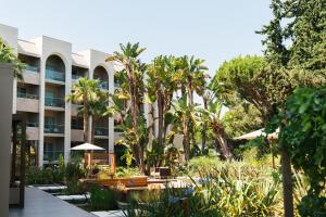 a resort with a garden and palm trees at Falésia Hotel - Adults Only in Albufeira