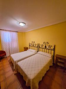 a bedroom with two beds and a yellow wall at Hotel-Albergue Puente Fitero in Itero de la Vega