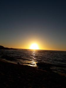 um pôr do sol na praia com o pôr do sol em Turquesa em El Quisco