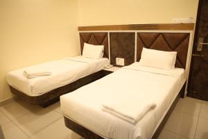 two beds in a hotel room with white sheets at Kings Residency in Chennai