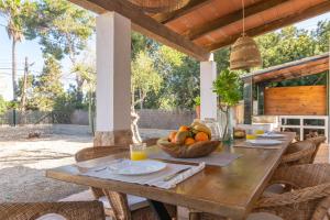 a wooden table with a bowl of fruit on a patio at Sol I Vent in Cala Santanyi