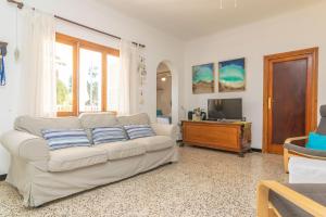 a living room with a white couch and a television at Sol I Vent in Cala Santanyi