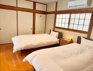 a room with two beds and two windows at かみくまハウス in Kumamoto