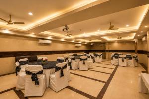 a banquet hall with white tables and chairs and ceiling at Airport La Sapphire Hotel & Restaurant in New Delhi