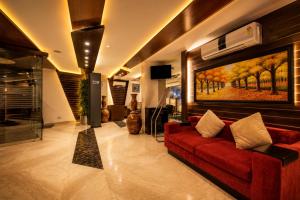 a living room with a red couch and a painting at Airport La Sapphire Hotel & Restaurant in New Delhi