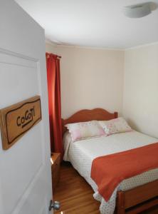 a small bedroom with a bed and a door at Hostal Alto Algarrobal in Combarbalá