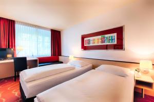 a hotel room with two beds and a tv at Welcome Kongress Hotel Bamberg in Bamberg