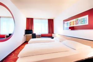 a hotel room with two beds and a mirror at Welcome Kongress Hotel Bamberg in Bamberg +13 photos