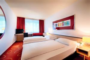 a hotel room with two beds and a tv at Welcome Kongress Hotel Bamberg in Bamberg