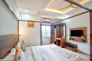 a hotel room with a bed and a television at De Alcazar Calangute in Calangute