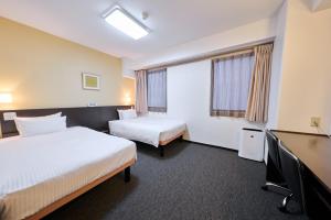 a hotel room with two beds and a desk at Smile Hotel Tokyo Nihonbashi in Tokyo