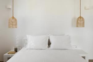 a white bed with two white pillows and two lights at Halo Tinos - PHOEBUS in Tinos