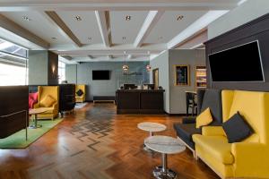 a lobby with yellow furniture and a flat screen tv at Park Inn by Radisson Bucharest Hotel & Residence in Bucharest