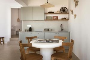 a white kitchen with a white table and chairs at Halo Tinos - PHOEBUS in Tinos +14 photos