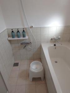 a bathroom with a white tub and a toilet and a sink at ペンションsakuraRIGHT in Motobu