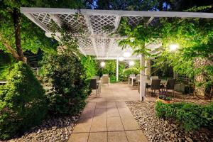 a patio with tables and chairs under a white pergola at Papuga Park Hotel Wellness Marrakesz & SPA in Bielsko-Biała