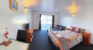 a room with a bed and a desk and a tv at Kerry's Motel in Rotorua