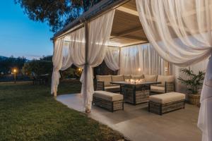 a patio with a table and chairs and curtains at Agrilia Hotel Adults Only in Laganas
