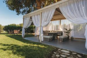 a pavilion with white curtains and a table and chairs at Agrilia Hotel Adults Only in Laganas