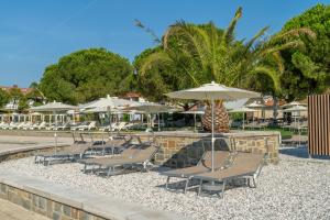 a group of chairs and umbrellas next to a pool at Hotel Vile Park Premium in Portorož