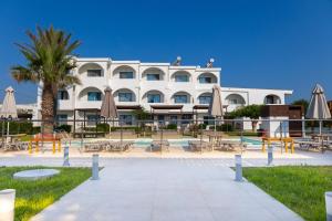 a large white building with tables and umbrellas at Beach Break Rhodes in Faliraki