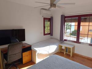 a bedroom with a bed and a desk and a tv at Casa Cármenes del Mar in Almuñécar
