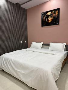 a bedroom with a large white bed with a picture on the wall at Hotel Pravas Inn in Lucknow