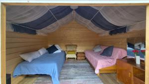two beds in a room with a tent at Pikku aitta in Heikkilä