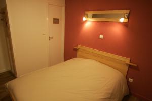 a small bedroom with a bed and a red wall at Hôtel Bar Restaurant de la Poste Le 1900 in Jougne +7 photos