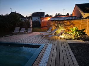 a deck with lounge chairs and a swimming pool at Lodge avec piscine chauffée privative et ou Studio avec son SPA, SAUNA HAMAMM privatifs in Cepoy