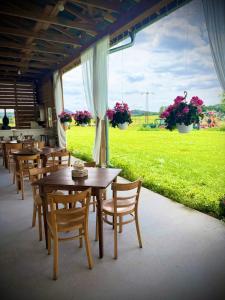 a restaurant with wooden tables and chairs and a green field at Farma P&P Apartmány in Vrchovany