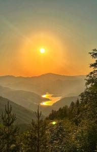 a sunset in the mountains with the sun setting over a valley at BiSER PANČIĆA in Sekulić 