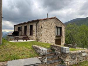 a small stone building with a bench and a picnic table at Cal Mureu in Pardines