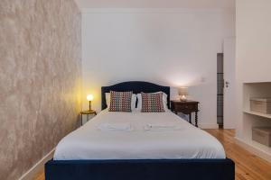 a bedroom with a large white bed with two tables at A cozy hideout in Lisbon