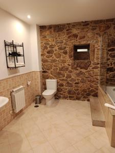 a bathroom with a toilet and a stone wall at Casa Ceferinos in Muxia