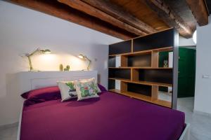 a bedroom with a purple bed and shelves at Sotto la torre Apartment in Cagliari