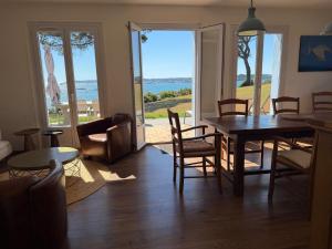 a living room with a table and chairs and a view of the ocean at La Bretonne vue mer in Lanmodez
