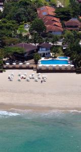 eine Luftansicht auf einen Strand mit Stühlen und Pools in der Unterkunft Coconut's Maresias Hotel in Maresias