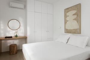 a white bedroom with a white bed and a mirror at Halo Tinos - ARTEMIS in Tinos