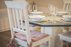 a dining room table with glasses and a white chair at Sharky Bay in Keitum