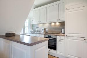 a kitchen with white cabinets and a counter top at Sharky Bay in Keitum +20 photos