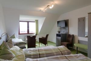a hotel room with two beds and a tv at Gästehaus Ainser in Hagnau