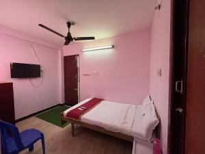 a small room with a bed and a ceiling fan at Hotel Bypass in Madurai