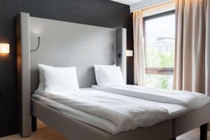a bed with white sheets and pillows next to a window at Scandic Stavanger Park in Stavanger