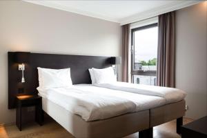 a bedroom with a large bed with a large window at Scandic Stavanger Park in Stavanger +42 photos