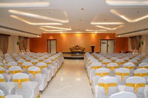 a banquet hall with white chairs and a stage at Hotel G Grand Inn in Thanjāvūr