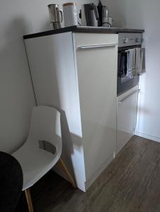 a kitchen with a white counter and a white chair at Apfelblüte in Stockach