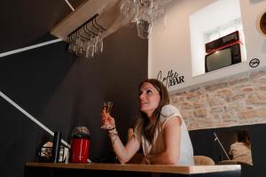 a woman sitting at a table holding a glass of wine at Mariposa cinema in Grumo Appula