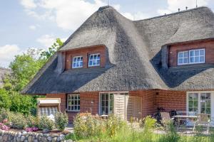 a thatch roofed house with windows and a patio at Düne in Keitum