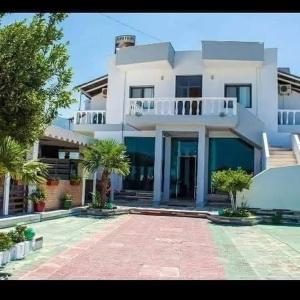 a large white house with palm trees in front of it at Onde Rooms in Vlorë